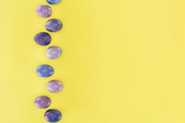 Vista superior de huevos de Pascua pintados de púrpura, aislados sobre fondo amarillo - foto de stock