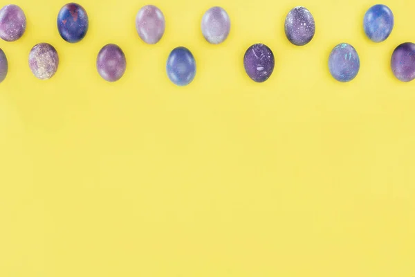 Top view of purple painted easter eggs, isolated on yellow with copy space — Stock Photo