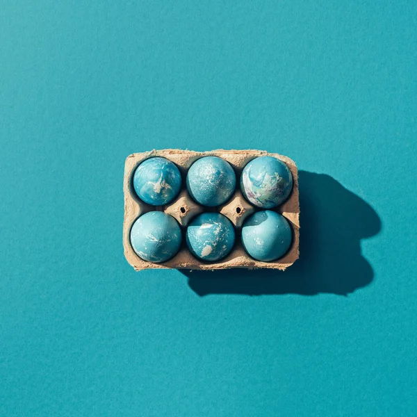 Vue du dessus des œufs de Pâques bleus dans le plateau, sur bleu — Photo de stock