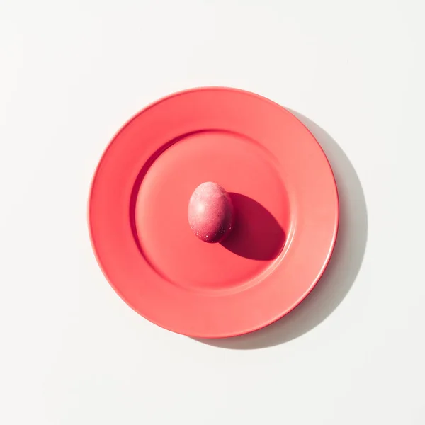 Вид зверху пухнасте червоне пасхальне яйце на червоній тарілці, на білому — стокове фото