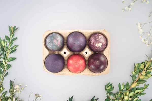 Top view of traditional easter eggs in tray with leaves and flowers, isolated on white — Stock Photo