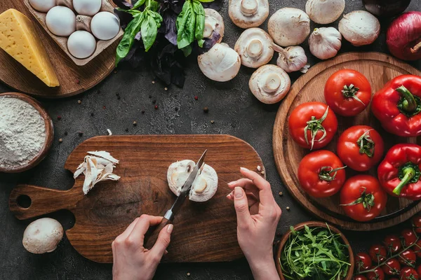 Colpo ritagliato di donna che taglia funghi per pizza sul tavolo di cemento — Foto stock