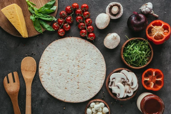 Vista dall'alto di pasta di pizza con varie verdure per la guarnizione su tavolo di cemento — Foto stock