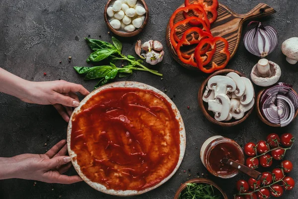 Recadrée shoto de femme préparation de pizza maison sur table en béton — Photo de stock