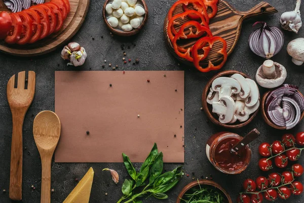 Vista superior de ingredientes de pizza y papel en blanco sobre mesa de hormigón - foto de stock