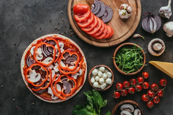 Top view of uncooked pizza with ingredients on concrete table — Stock Photo