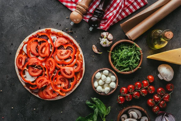 Vista dall'alto della pizza cruda con vari ingredienti sul tavolo di cemento — Foto stock