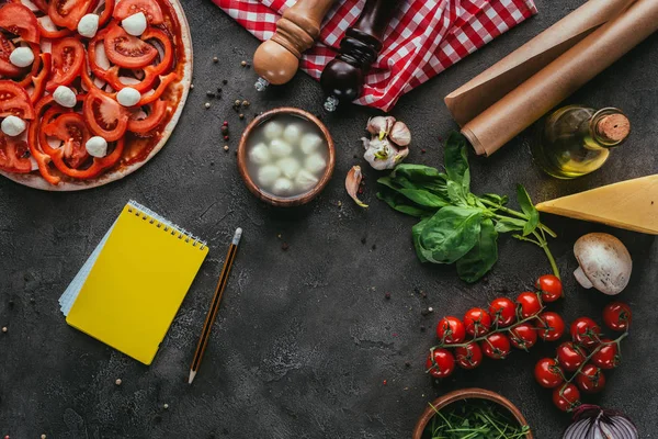 Vista superior de pizza não cozida com notebook para receita em mesa de concreto — Fotografia de Stock