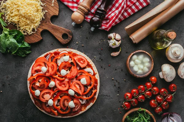 Top view of uncooked pizza with ingredients on concrete table — Stock Photo