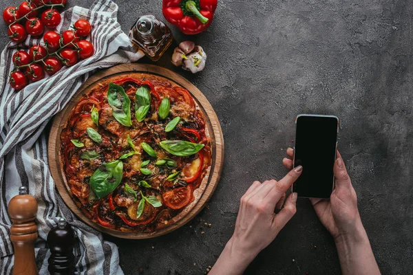 Ritagliato colpo di donna utilizzando smartphone su tavolo di cemento con pizza — Foto stock
