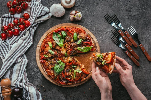 Colpo ritagliato di donna che prende pezzo di pizza appena sfornata — Foto stock
