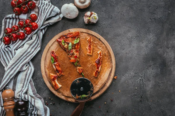 Вид сверху на куски съеденной пиццы с резаком на бетонном столе — стоковое фото