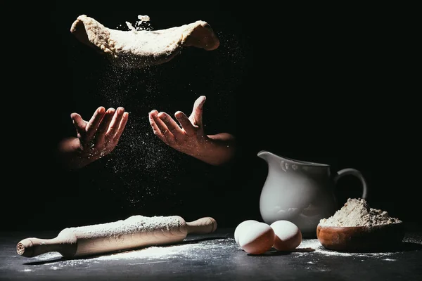 Cropped shot of chef throwing up dough for pizza on black — Stock Photo
