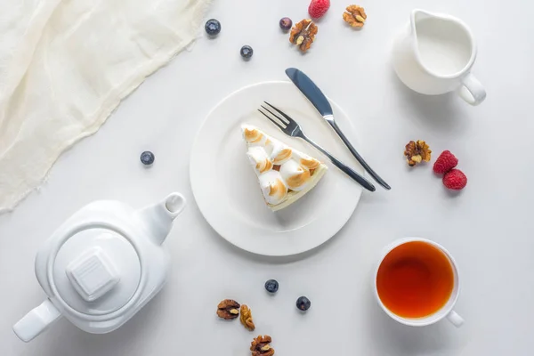Вид зверху на шматок торта з ягодами та чаєм на білому столі — стокове фото