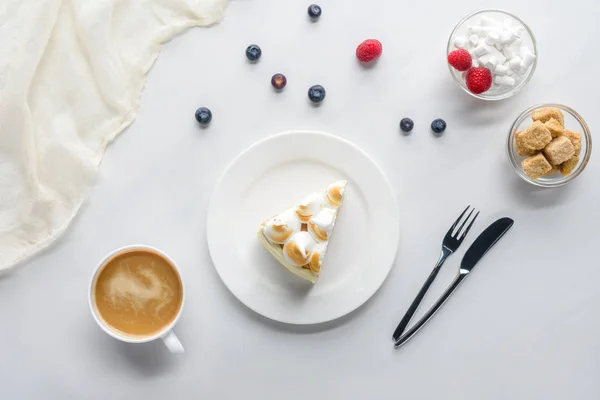 Blick von oben auf leckeres Stück Kuchen mit Beeren und Kaffee auf weißem Tisch — Stockfoto