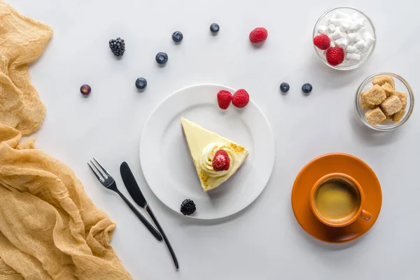 Vista superior del pedazo de pastel con bayas y café en la mesa blanca - foto de stock