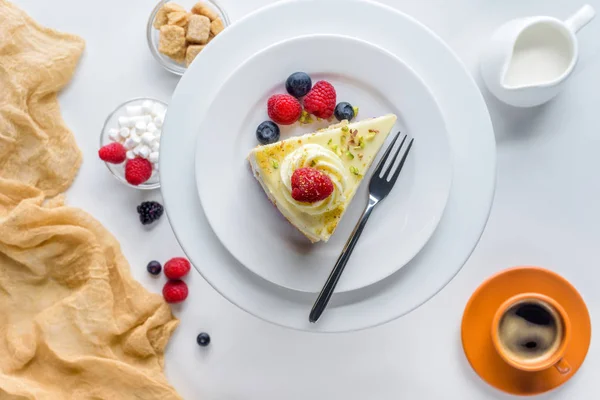 Vue du dessus du morceau de gâteau avec des baies sur la table blanche — Photo de stock