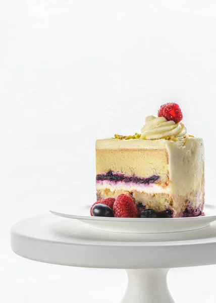 Morceau de gâteau appétissant sur support de gâteau blanc isolé sur blanc — Photo de stock