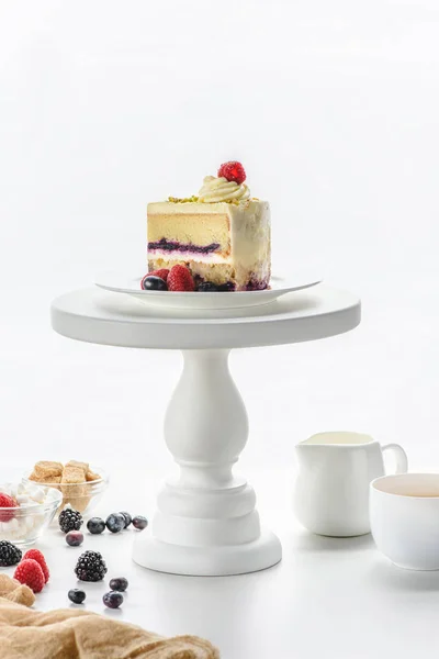 Pezzo di torta sul supporto del dolce bianco, caffè sul tavolo — Foto stock