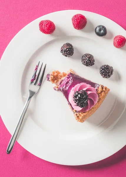 Vue de dessus du morceau mordu de tarte avec des baies sur la plaque sur la surface rose — Photo de stock