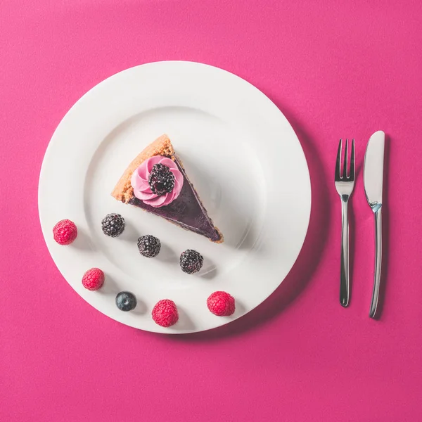 Top view of piece of cake with berries on plate on pink surface — Stock Photo