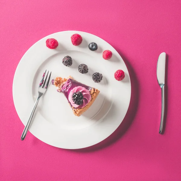 Вид сверху на кусок торта с ягодами на тарелке на розовой поверхности — стоковое фото