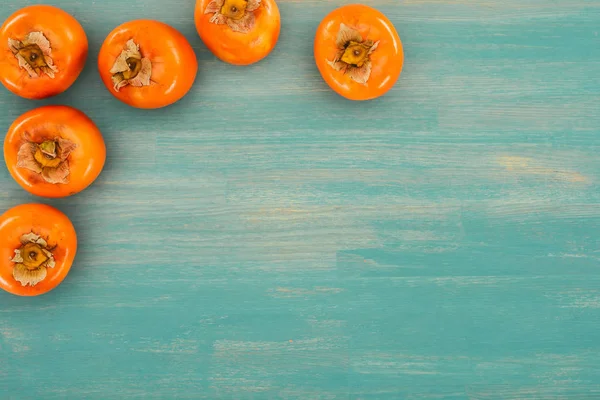 Top view of persimmons on turquoise wooden table — Stock Photo