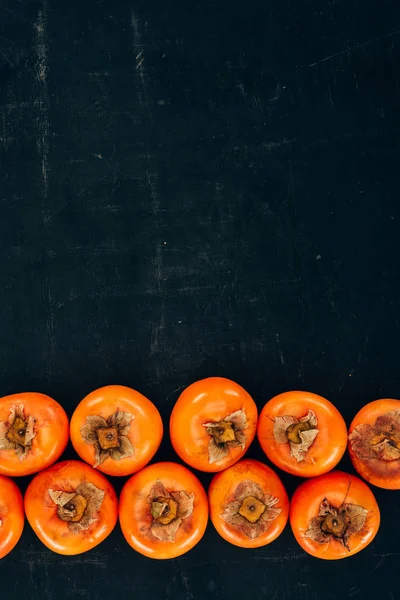 Top view of rows of ripe yummy persimmons on black — Stock Photo