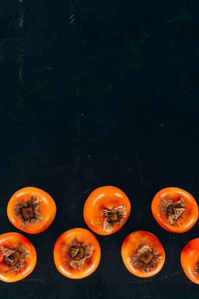 Top view of persimmons in rows on black — Stock Photo