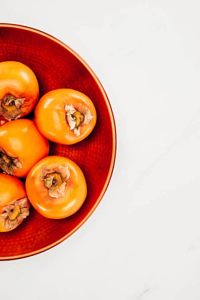 Top view of persimmons on red plate isolated on white — Stock Photo