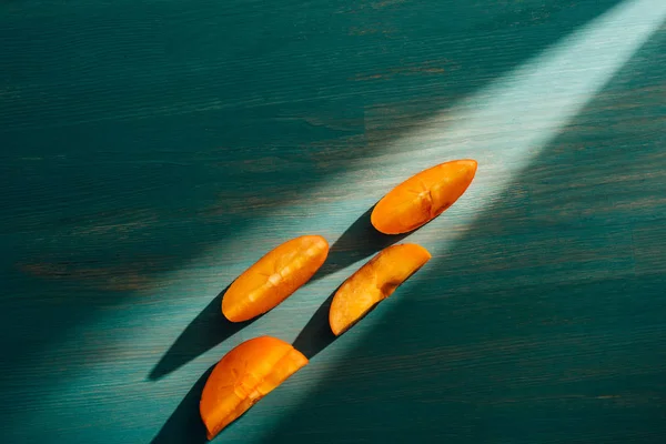 Top view of persimmon persimmon pieces on table with light and shadow — Stock Photo