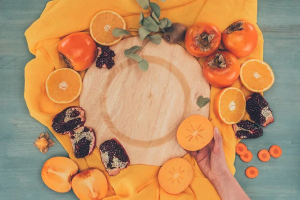 Cropped image of woman holding piece of persimmon — Stock Photo