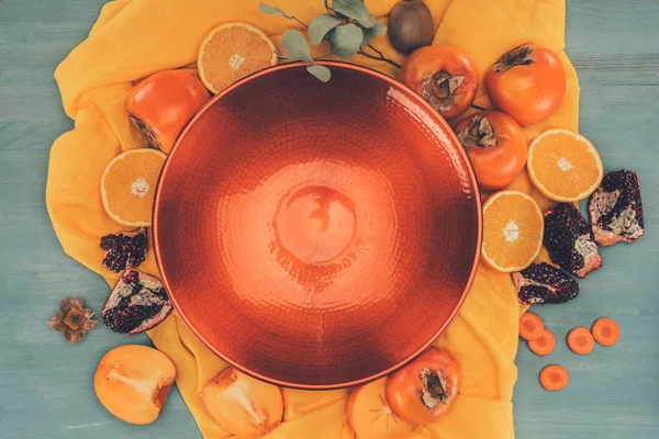 Top view of red plate and fruits on orange tablecloth — Stock Photo