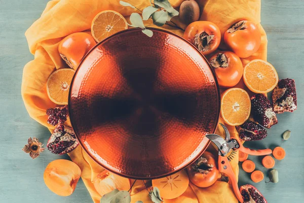 Vista superior da grande placa vermelha entre cáqui com laranjas e romãs — Fotografia de Stock