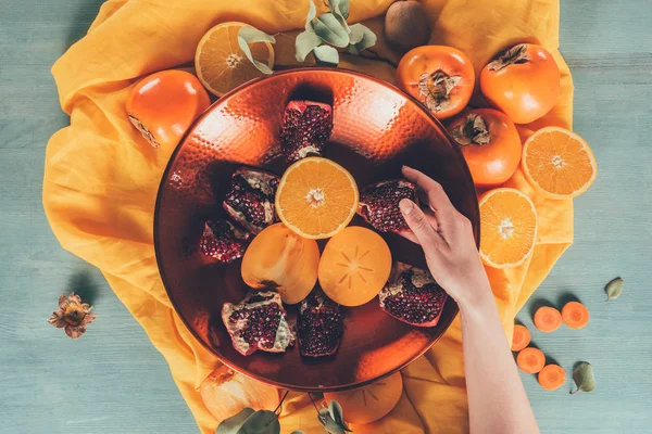 Immagine ritagliata di donna che prende pezzo melograno — Foto stock