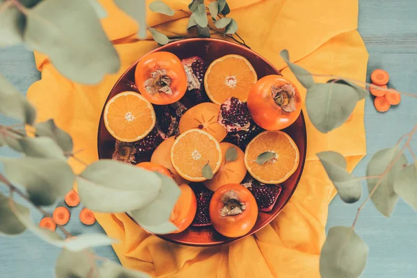 Vue de dessus des feuilles tombant sur les fruits sur assiette — Photo de stock