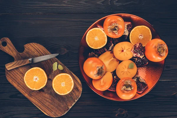 Вид сверху на фрукты на тарелке и деревянную доску — стоковое фото