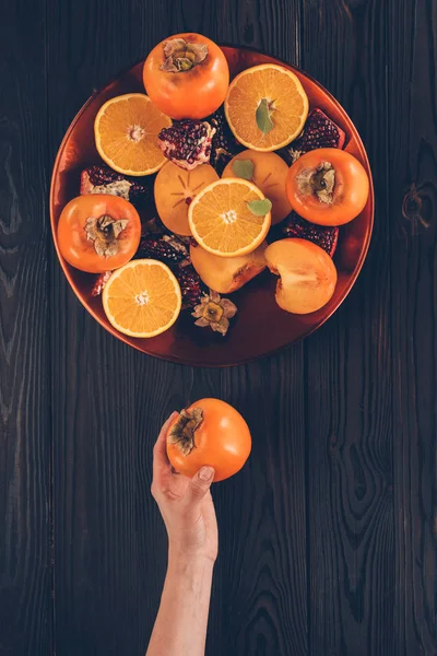 Cropped image of woman holding ripe persimmon — Stock Photo