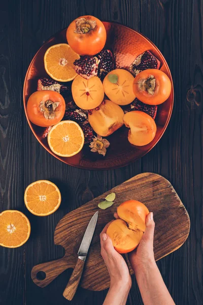 Cropped image of woman holding cut persimmon pieces — Stock Photo