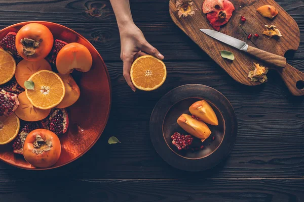 Cropped image of woman holding piece of orange — Stock Photo