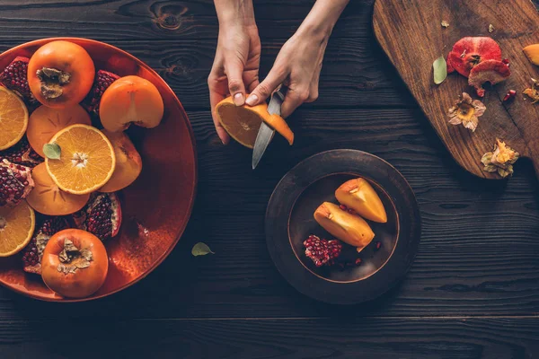 Imagen recortada de mujer pelando naranja - foto de stock