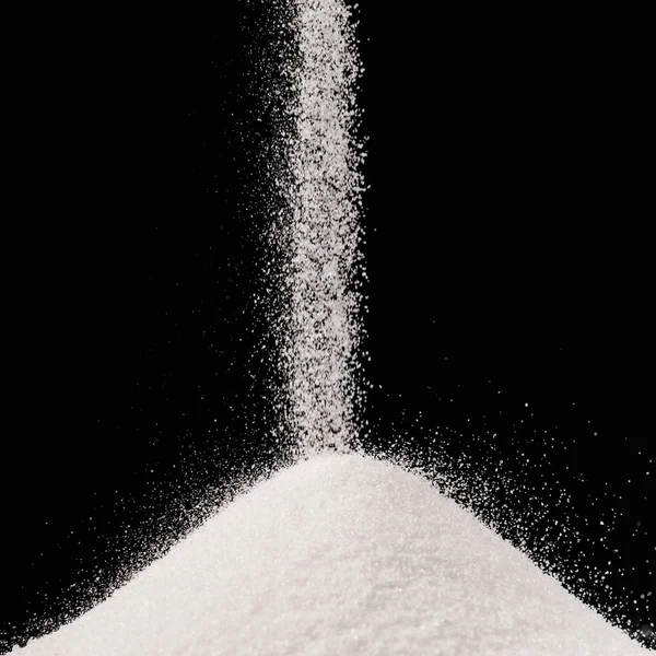 Azúcar que cae en la pila aislada en negro — Stock Photo