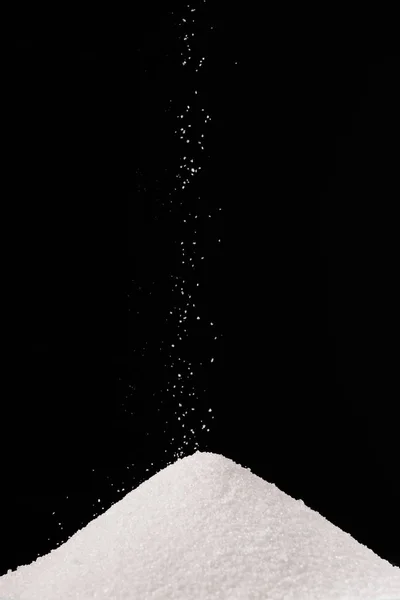 Açúcar branco caindo na pilha isolado no preto — Fotografia de Stock