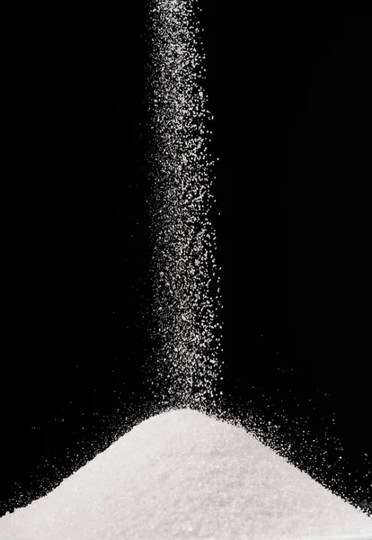 Sugar falling on pile isolated on black — Stock Photo