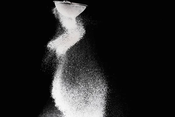 Sieve with falling flour isolated on black — Stock Photo