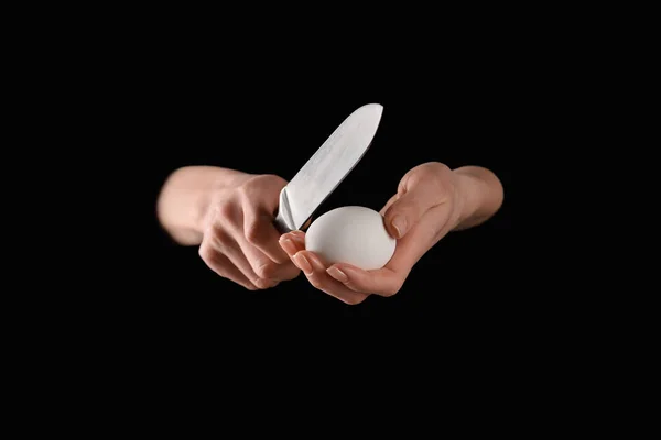 Cropped image of woman breaking chicken egg with knife isolated on black — Stock Photo