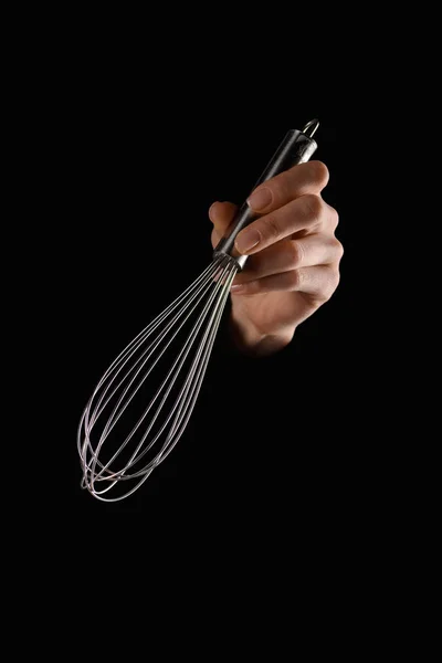 Imagem cortada de mulher segurando whisk na mão isolado em preto — Fotografia de Stock