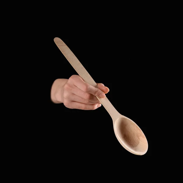 Cropped image of woman holding wooden spatula in hand isolated on black — Stock Photo