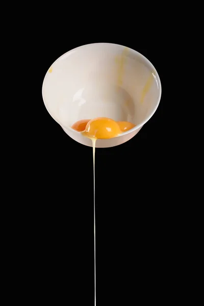 Tigela com derramamento de ovos de galinha isolados em preto — Fotografia de Stock