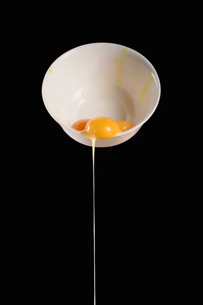 Bowl with pouring out chicken eggs isolated on black — Stock Photo